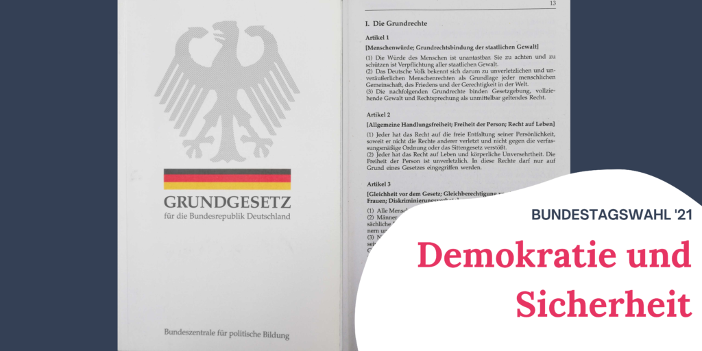 Auf dem Bild sieht man das Cover des Grundgesetztes und die erste Seite, auf der die Grundrechte aufgeschrieben sind. Rechts im Bild steht "Bundestagswahl '21 Demokratie und Sicherheit"